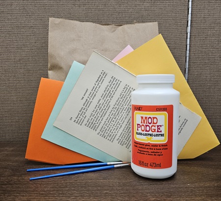 A pile of craft supplies consisting of colored paper, glue, and brushes.