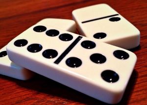 Three dominos on a table with the domino faces showing 6 dots, 5 dots, 2 dots, and a blank face.
